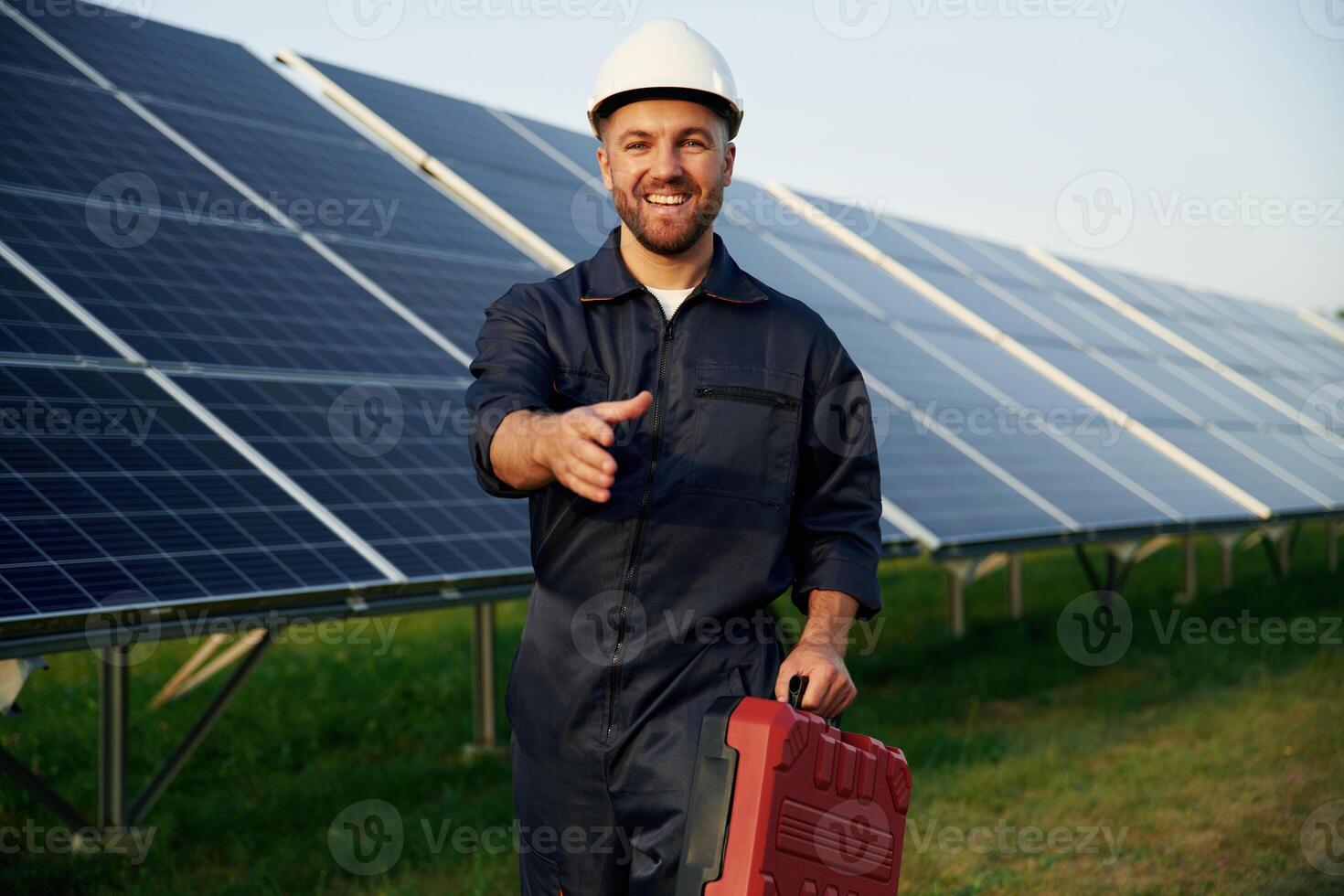 Red case in, hand. Man is working with solar panels outdoors at daytime photo