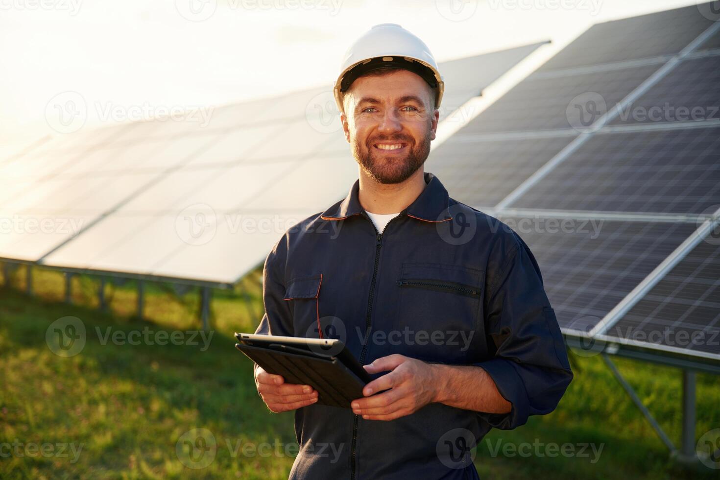 Digital ,tablet in,, hands. Man is working with solar panels outdoors at daytime photo