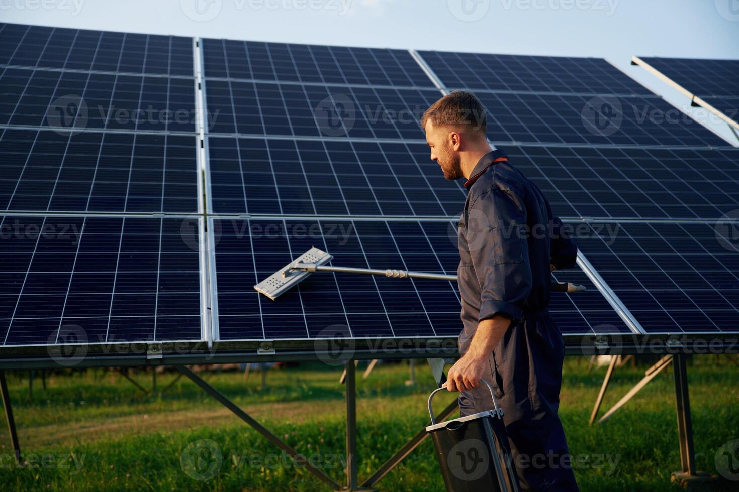 Side view,, cleaning, service. Man is working with solar panels outdoors at daytime photo