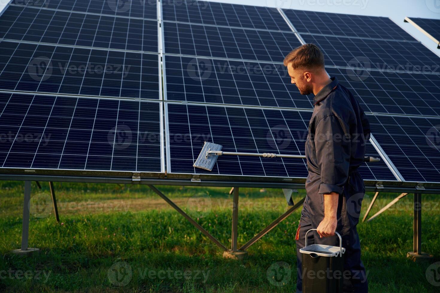 Side,, view, cleaning service. Man is working with solar panels outdoors at daytime photo