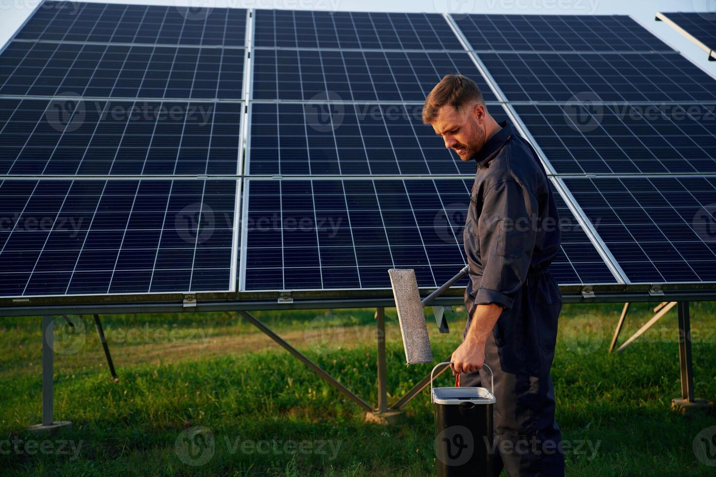 Side, view, cleaning service. Man is working with solar panels outdoors at daytime photo