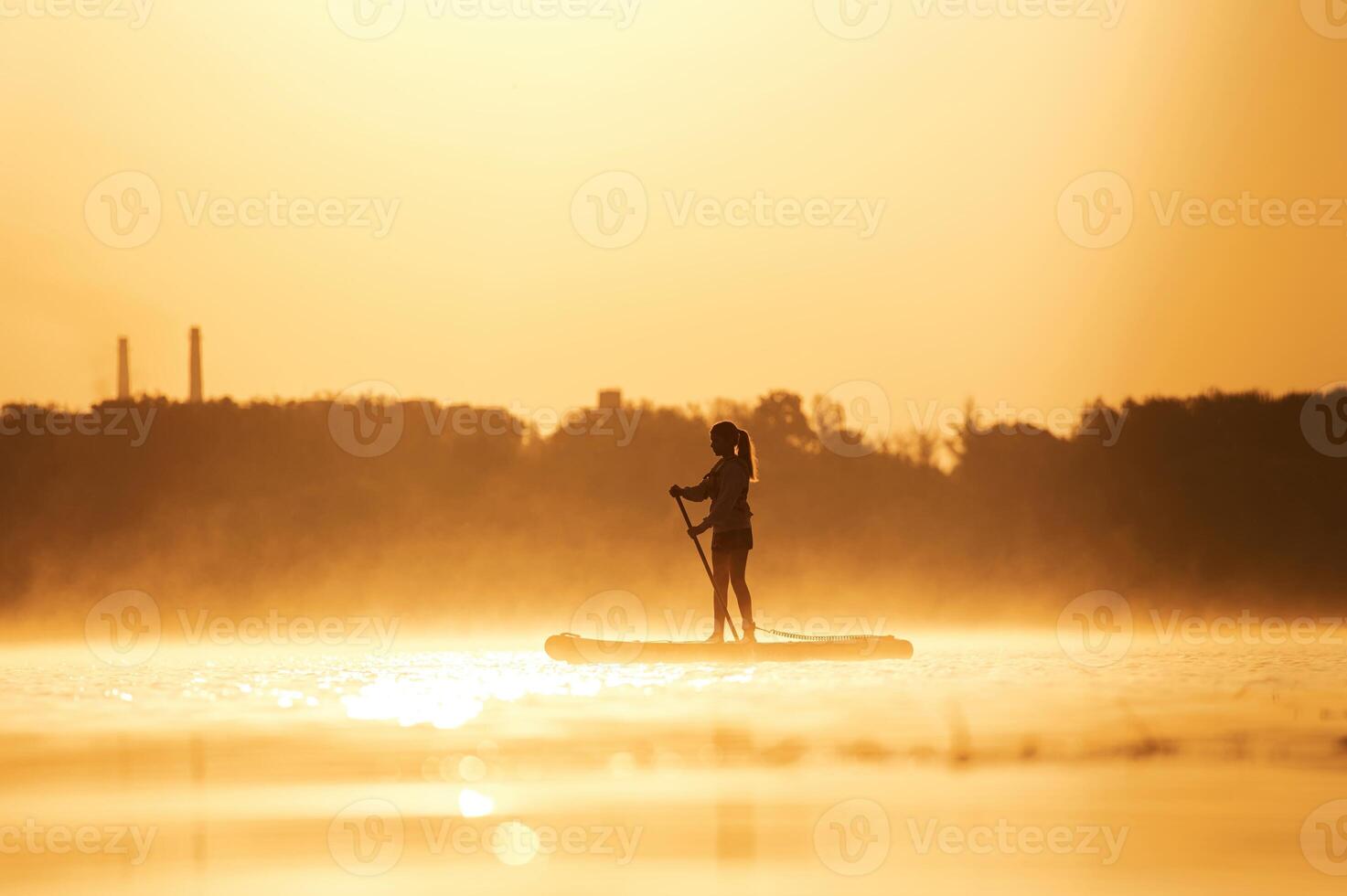Illuminated by,, sunlight. Girl kid is on the sup board, on the lake photo