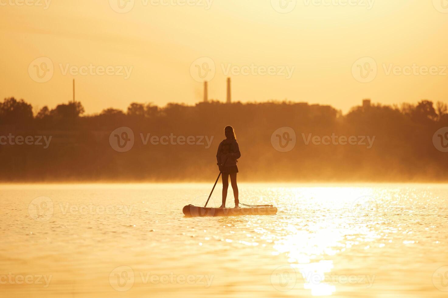 Illuminated by sunlight. Girl kid is on the ,,sup board, on the lake photo