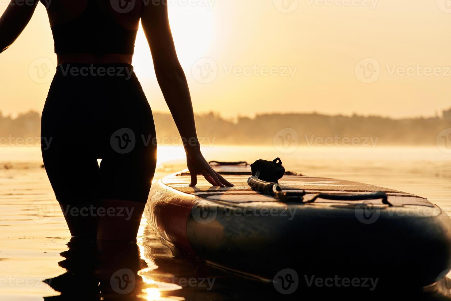 Black,, silhouette, sunset, illuminated. Young woman is with the sup board on the lake photo