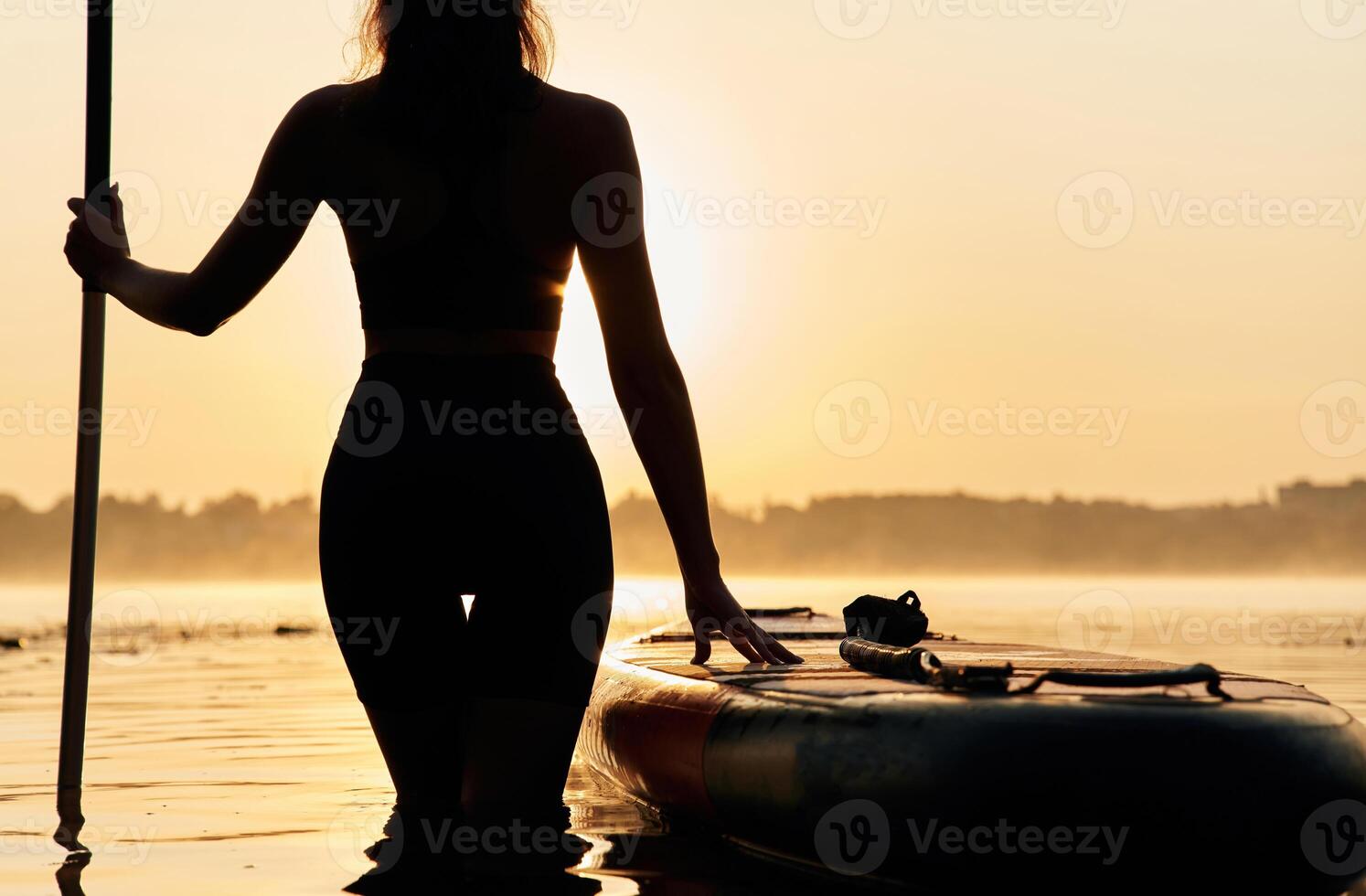 Black,, silhouette, sunset, illuminated. Young, woman is with the sup board on the lake photo
