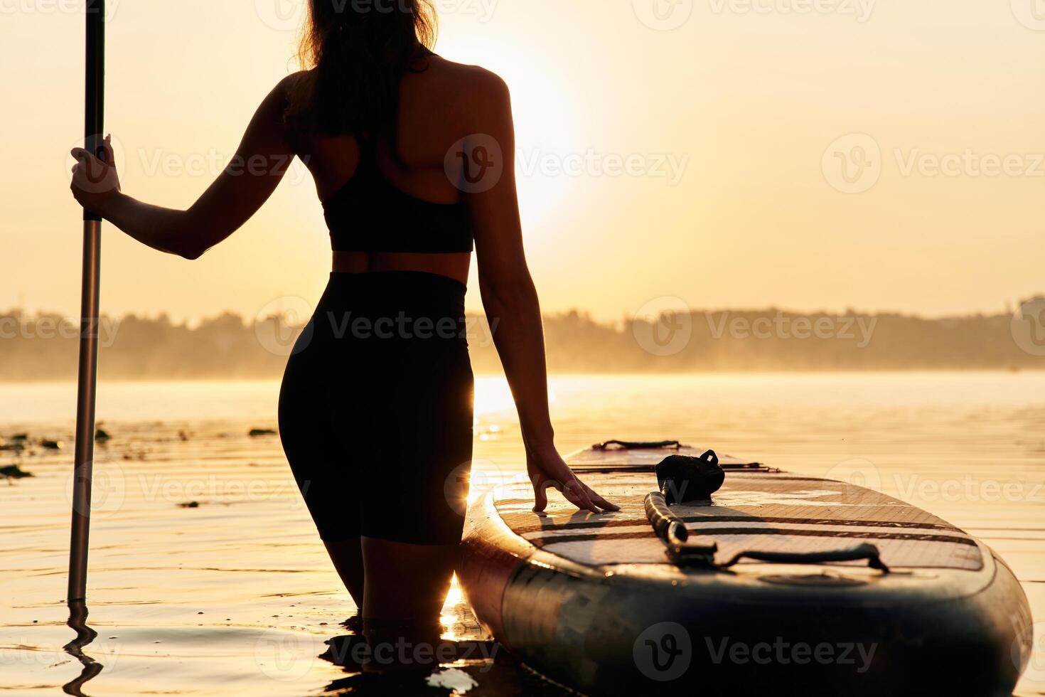 Majestic sunset, standing and looking. ...Young woman is with the sup board on the lake photo