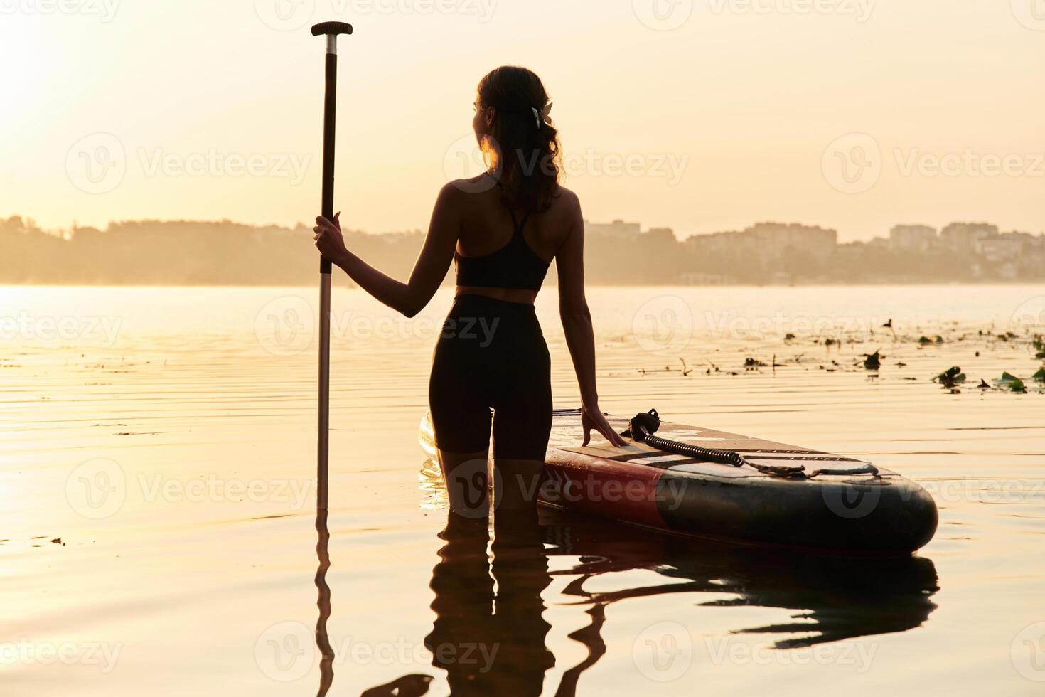 Enjoying,,, the sunset, illuminated. Young woman is with the sup board on the lake photo