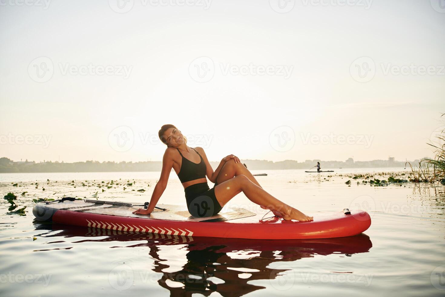 Taking a break, lying down on the sup board. Young woman is on the lake photo