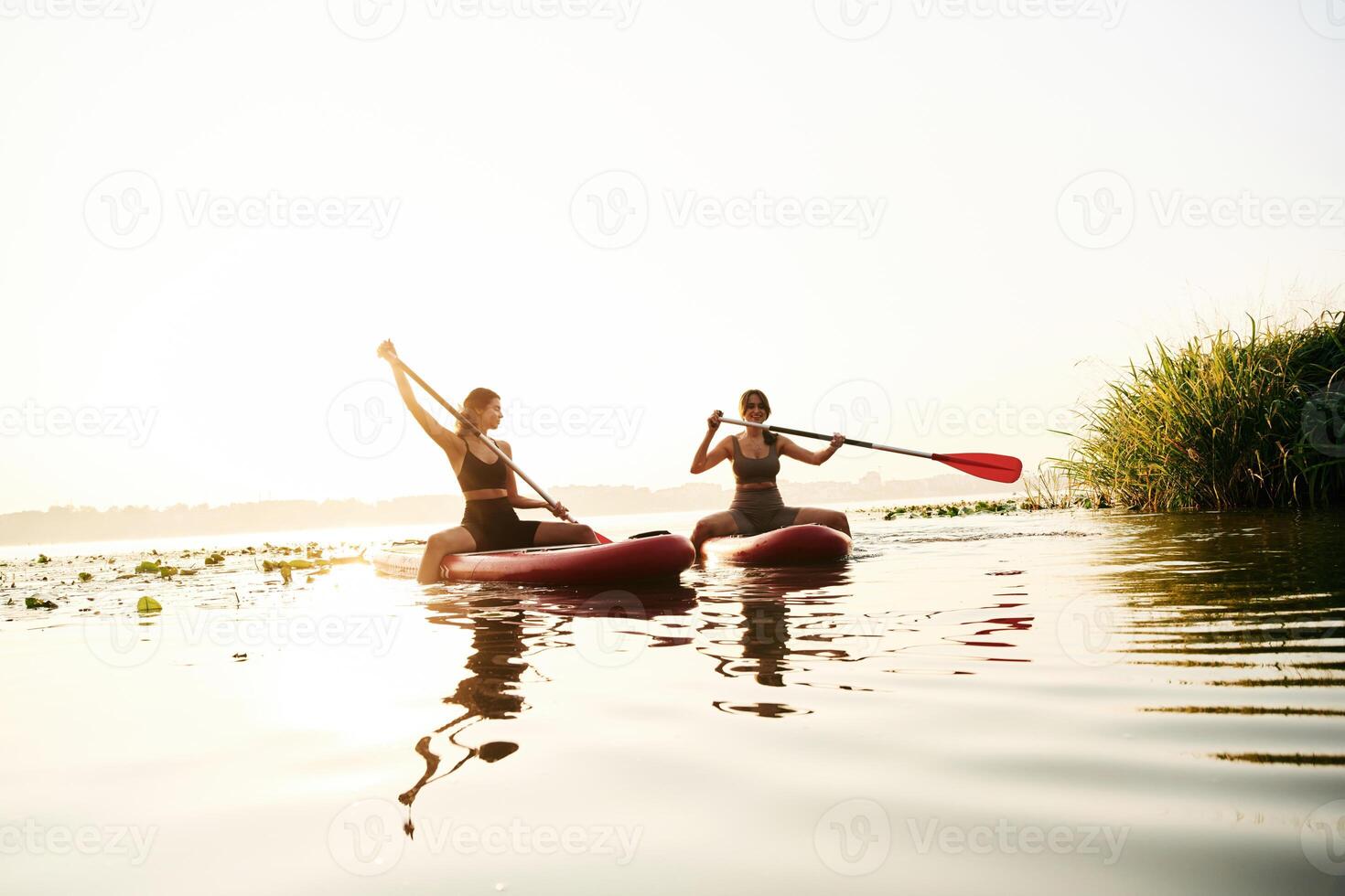Sport, conception. Women, friends are on sup board on the lake together photo