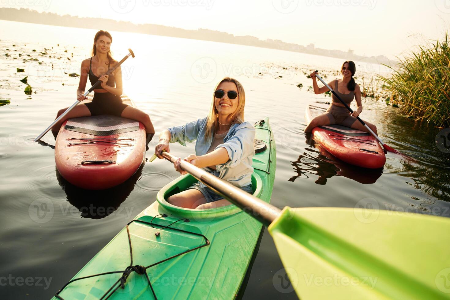 Taking a break.., Women friends are on sup board on the lake together photo