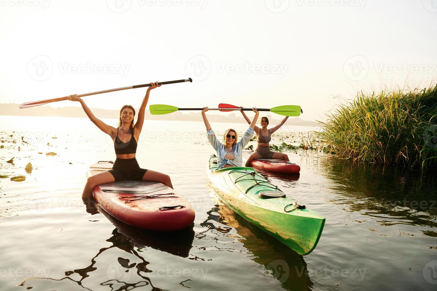 Finished,,, celebrating, hands up. Women friends are on sup board on the lake together photo