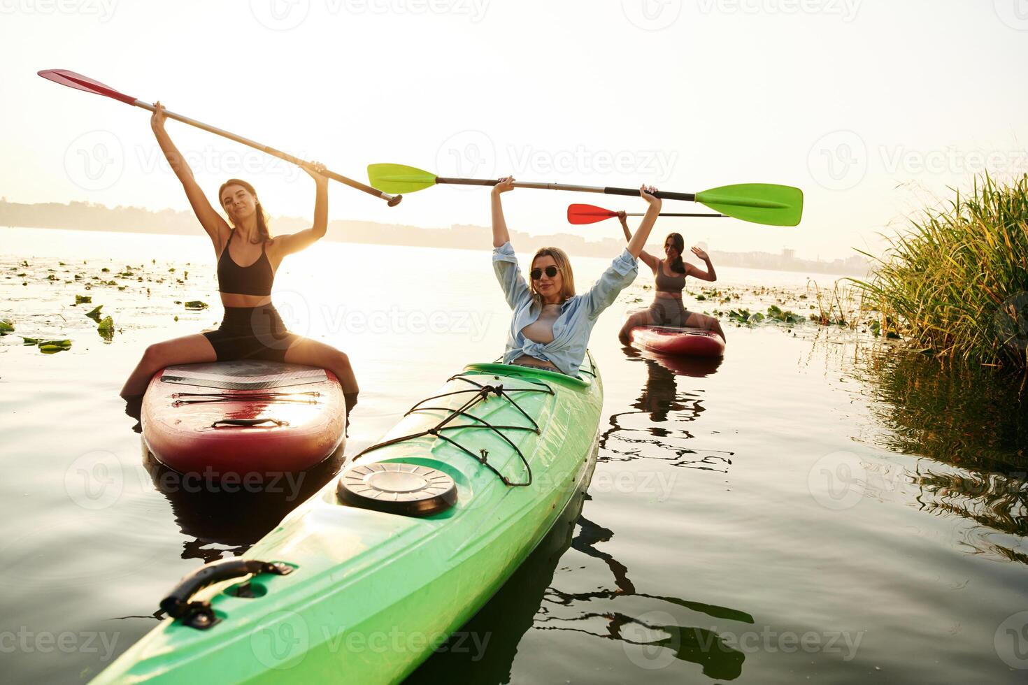 Finished,, celebrating, hands up. Women friends are on sup board on the lake together photo
