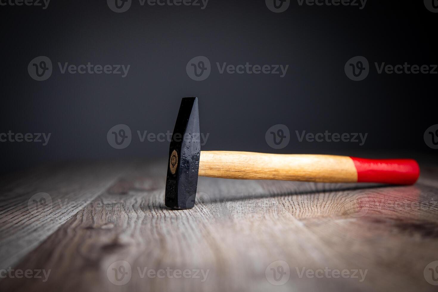 A hammer on a wooden table with a red handle photo