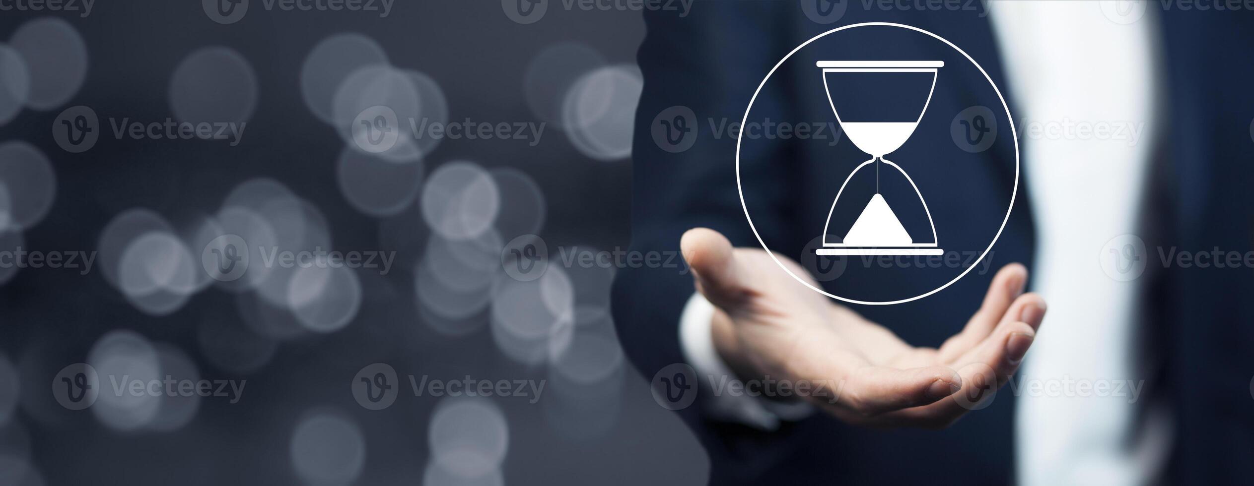Businessman holding hourglass icon on blurred background photo