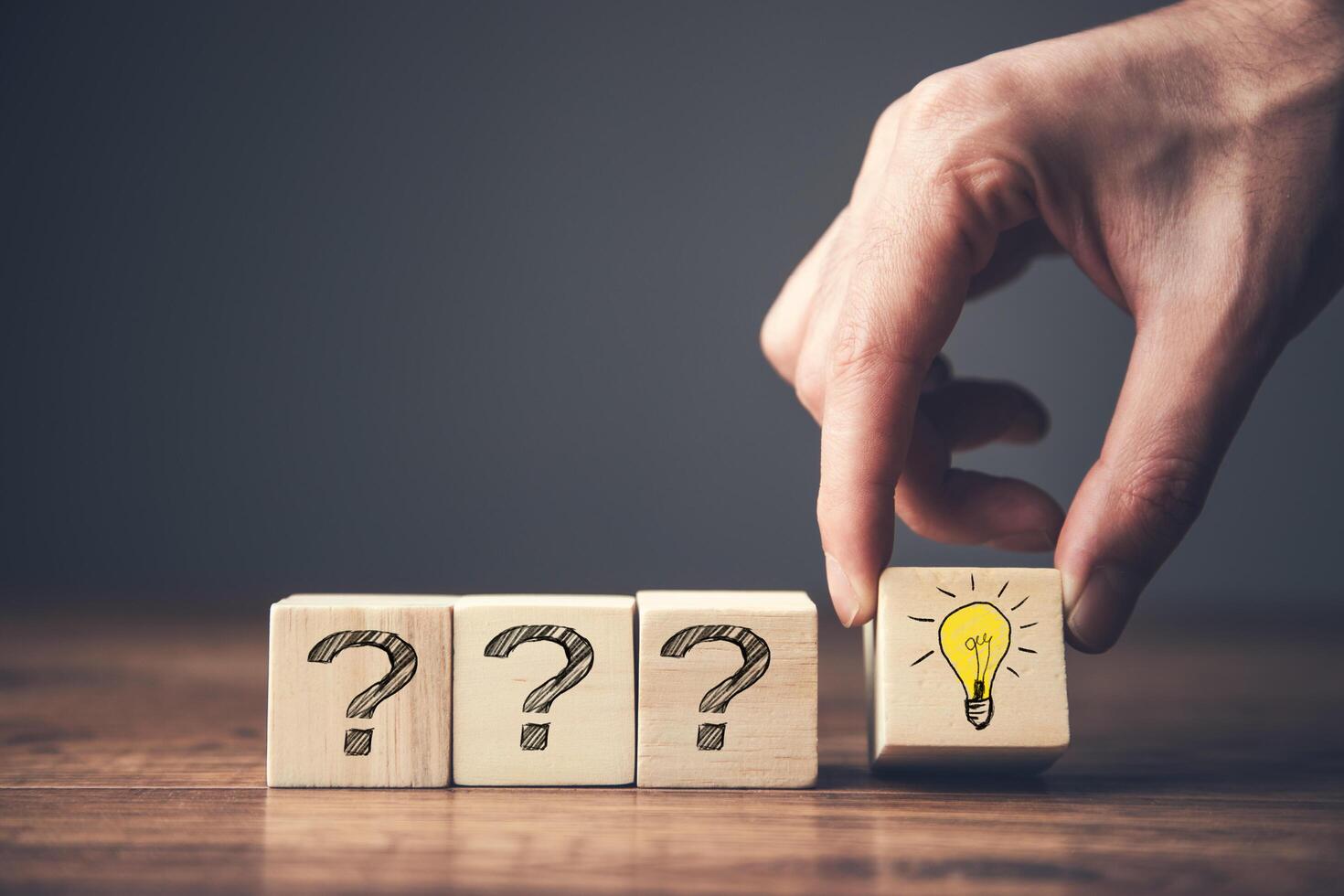 Hand placing question mark on wooden blocks with light bulb photo