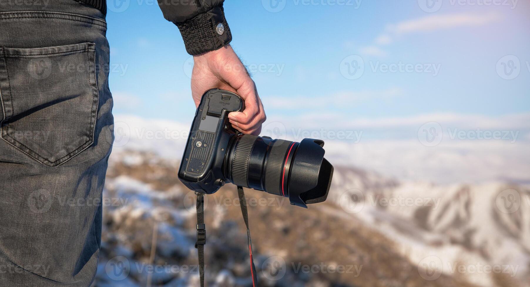 A person holding a camera on top of a mountain photo
