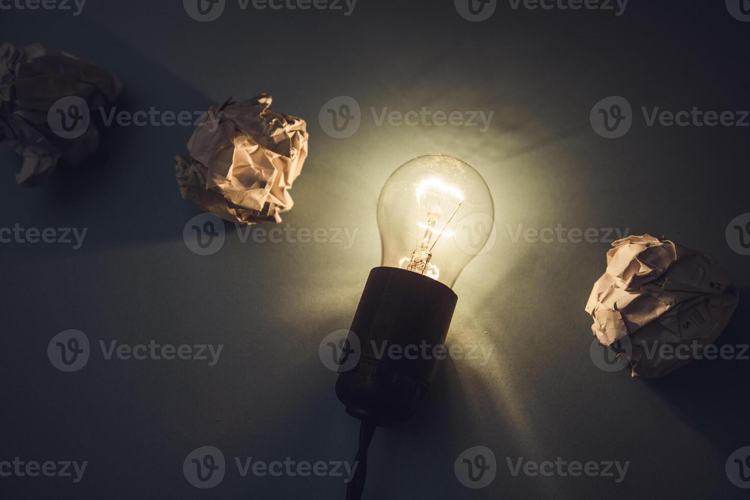 A light bulb and crumpled paper on a dark background photo