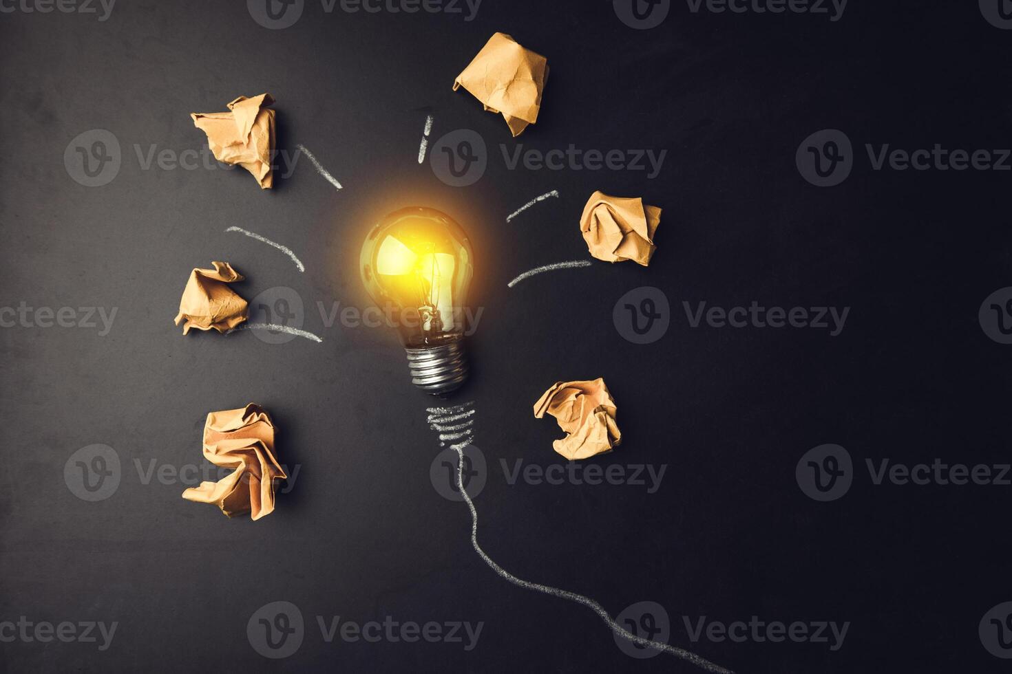 Light bulb with crumpled paper and sticky notes on a black background photo