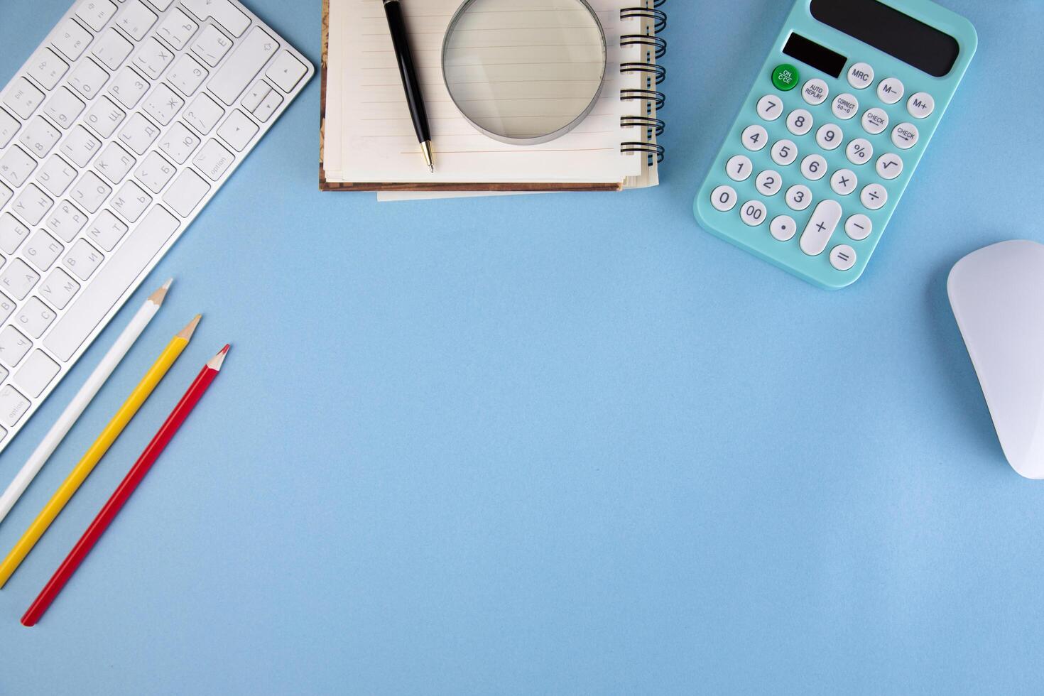 A desk with a keyboard, mouse, calculator, pencils, and other items photo