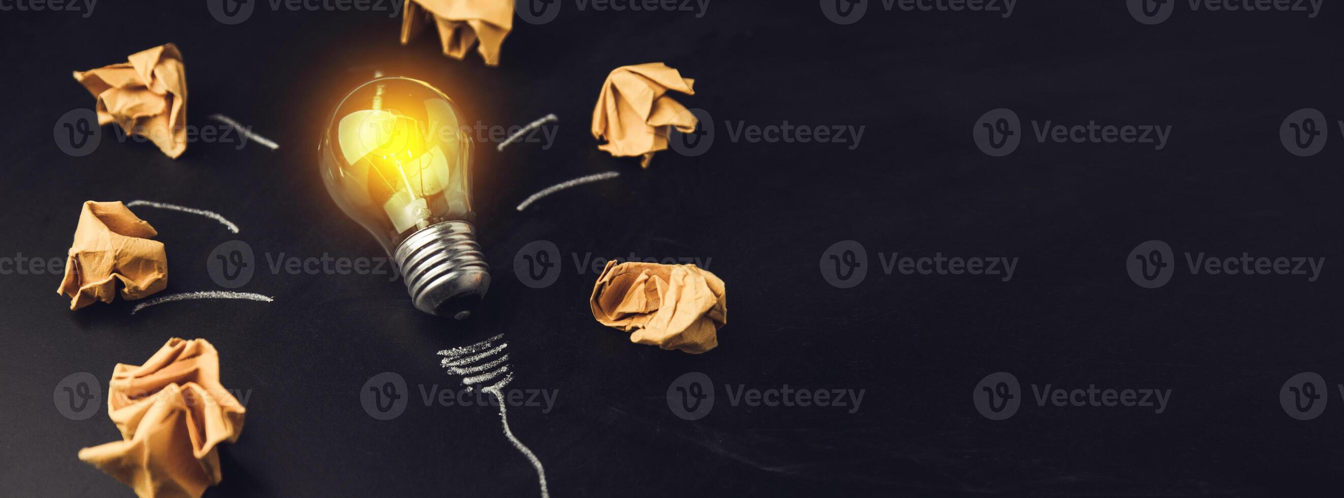A light bulb surrounded by paper and crumpled up paper photo