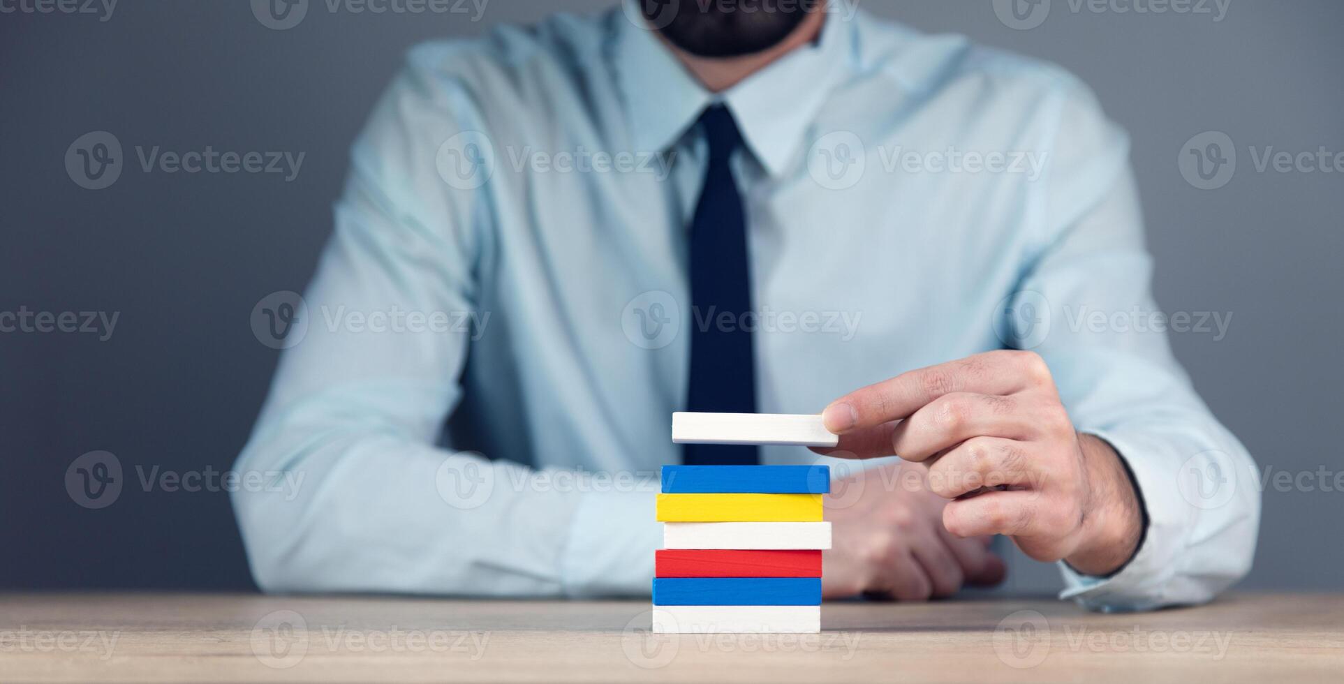 A man in a shirt and tie is holding a stack of colored cards photo