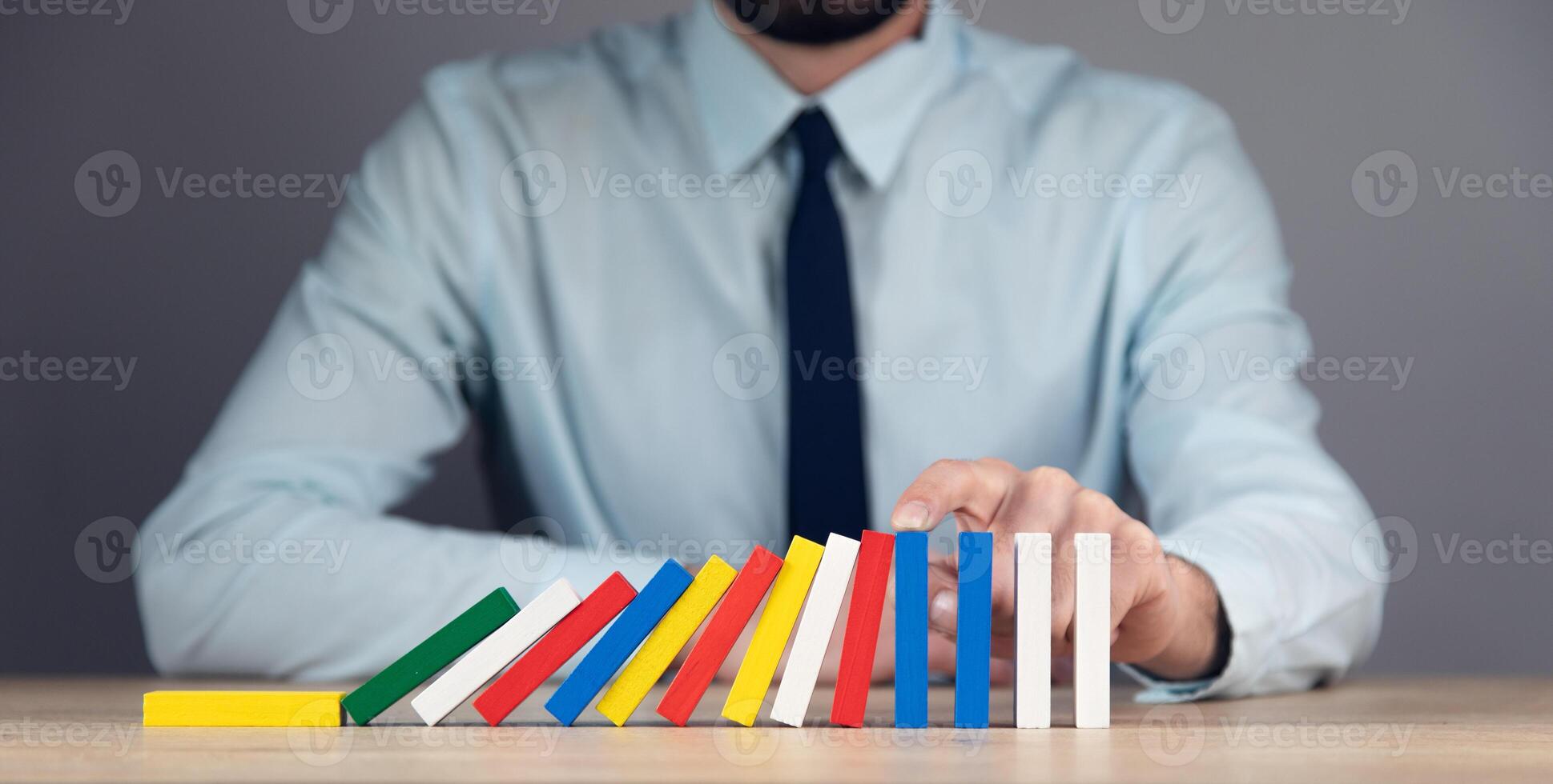 Businessman playing dominoes with colorful blocks photo