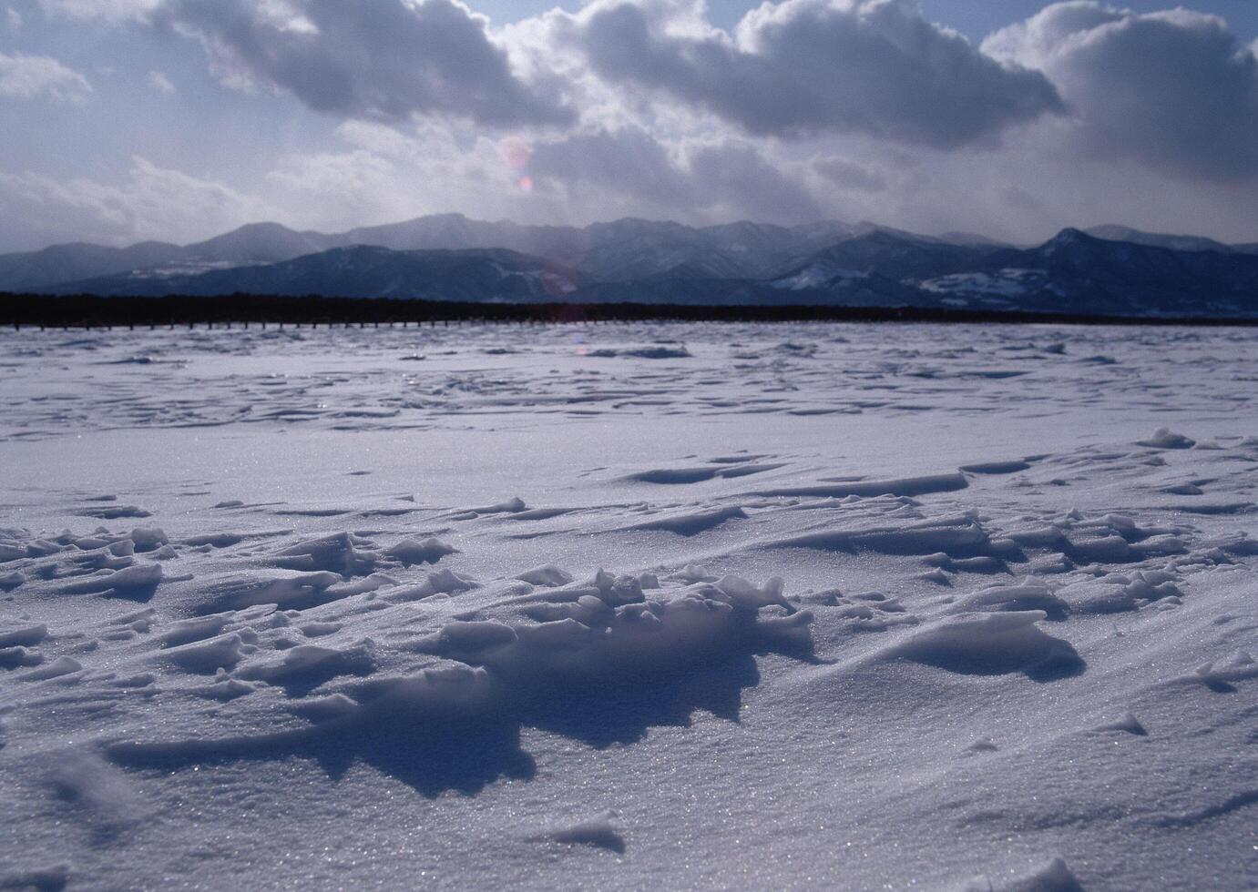 a snowy field with mountains in the background photo
