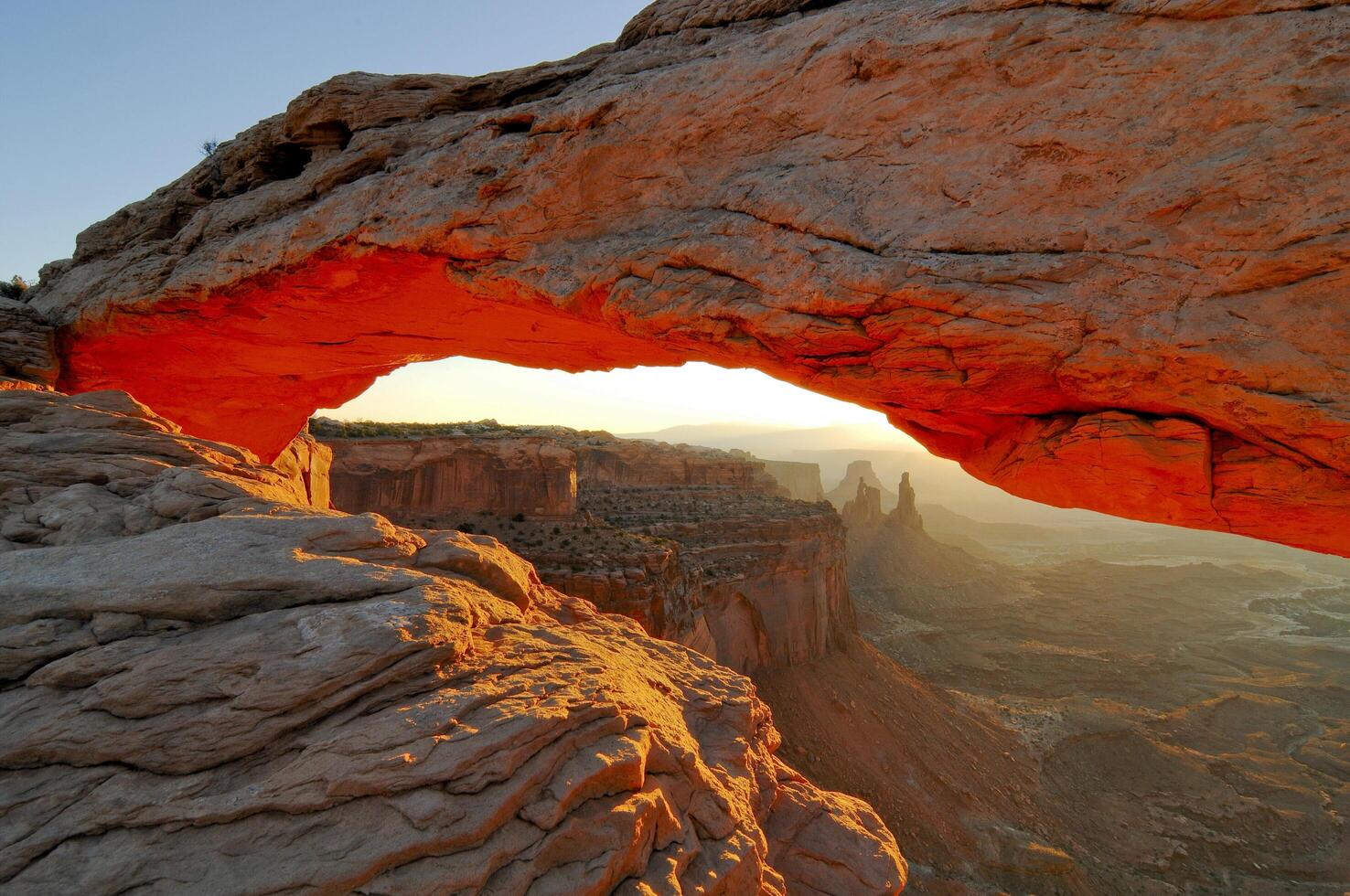 a large arch is seen in the desert at sunset photo