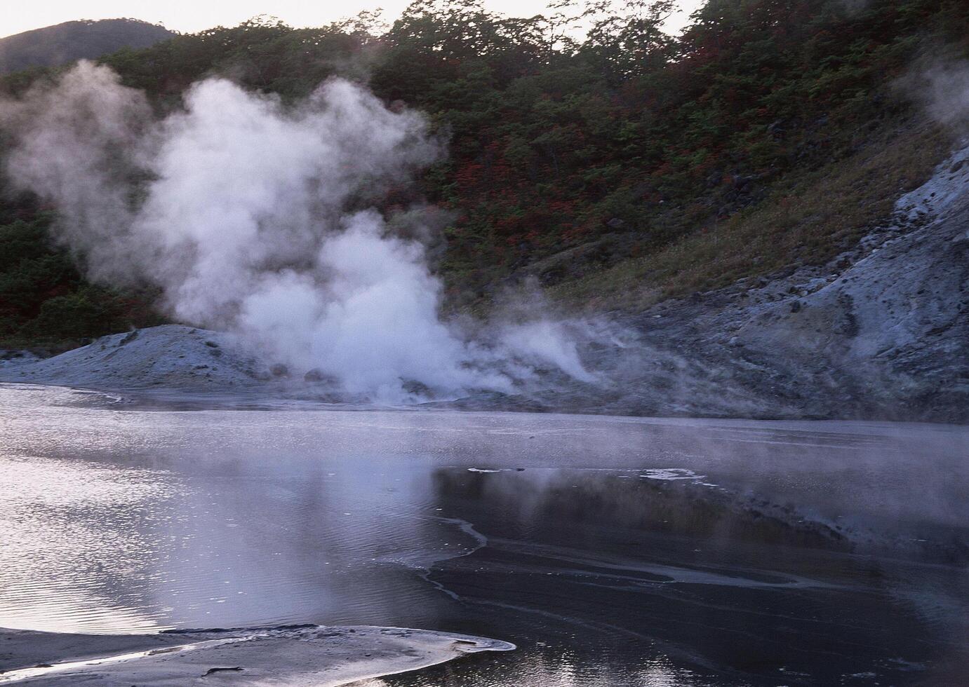 a man standing on a hill with a steam coming out of the ground photo