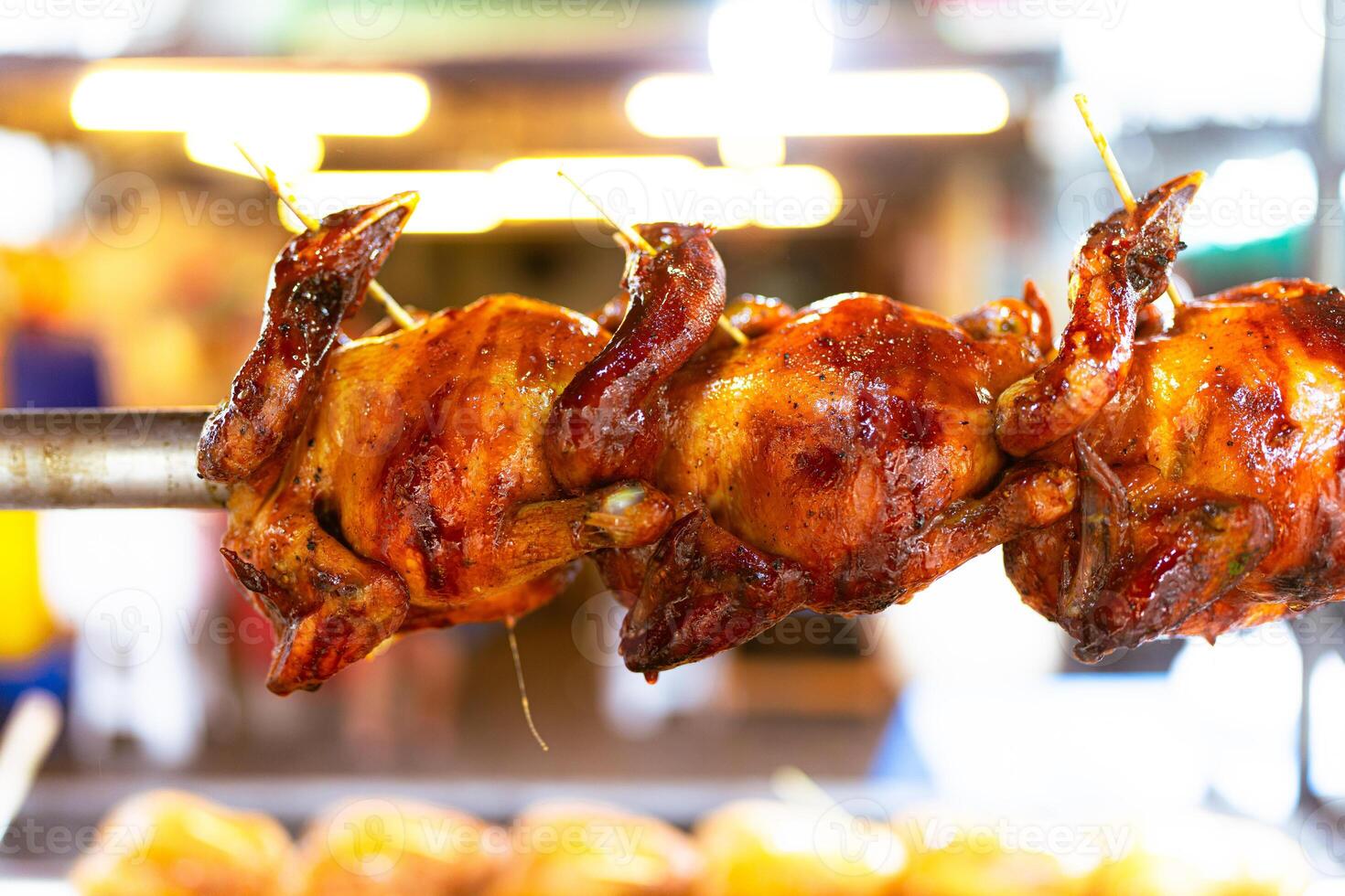 Grilled chicken swirl on the stove. Whole chicken skewers are arranged on a stainless steel skewer. photo