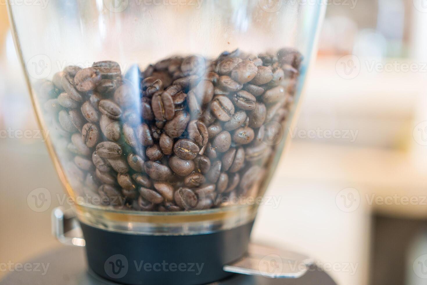 Coffee beans inside the grinder coffee machine at coffee shop. photo