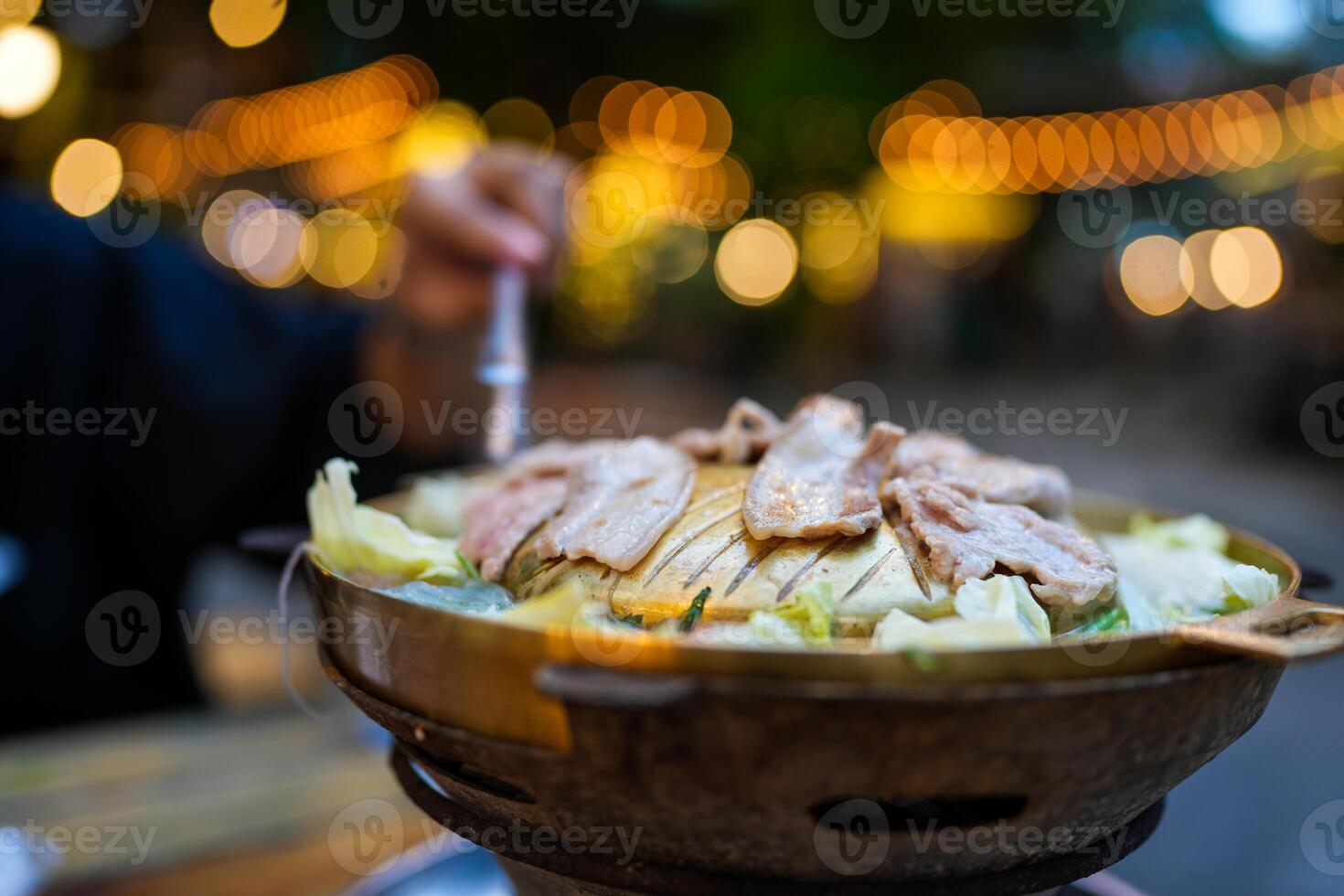 Thai barbecue grill pork on brass pan against bokeh background photo