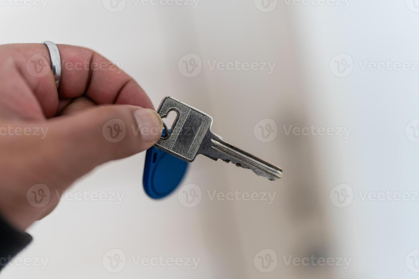 A photo of a hand gripping a key in front of a blurred background