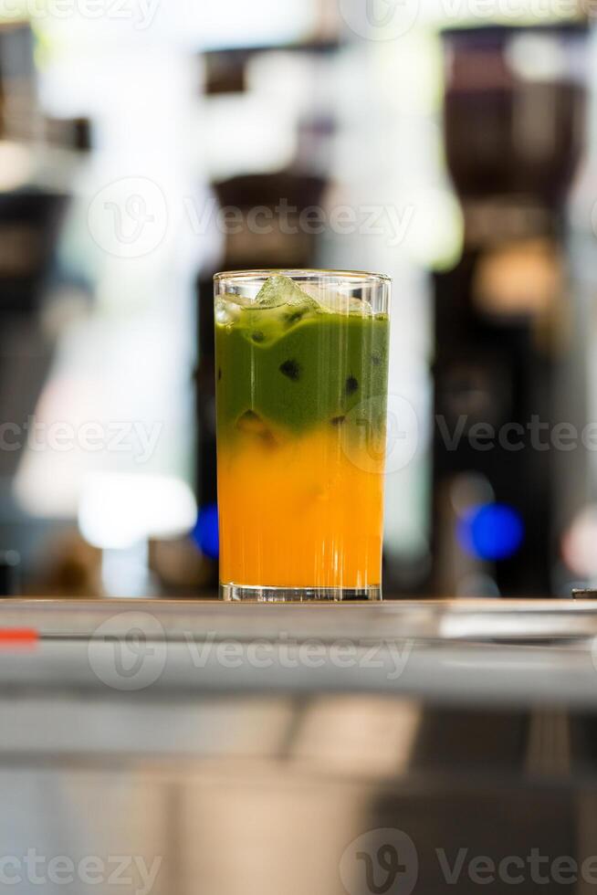 Iced matcha latte separated layers, matcha green tea with fresh orange juice photo