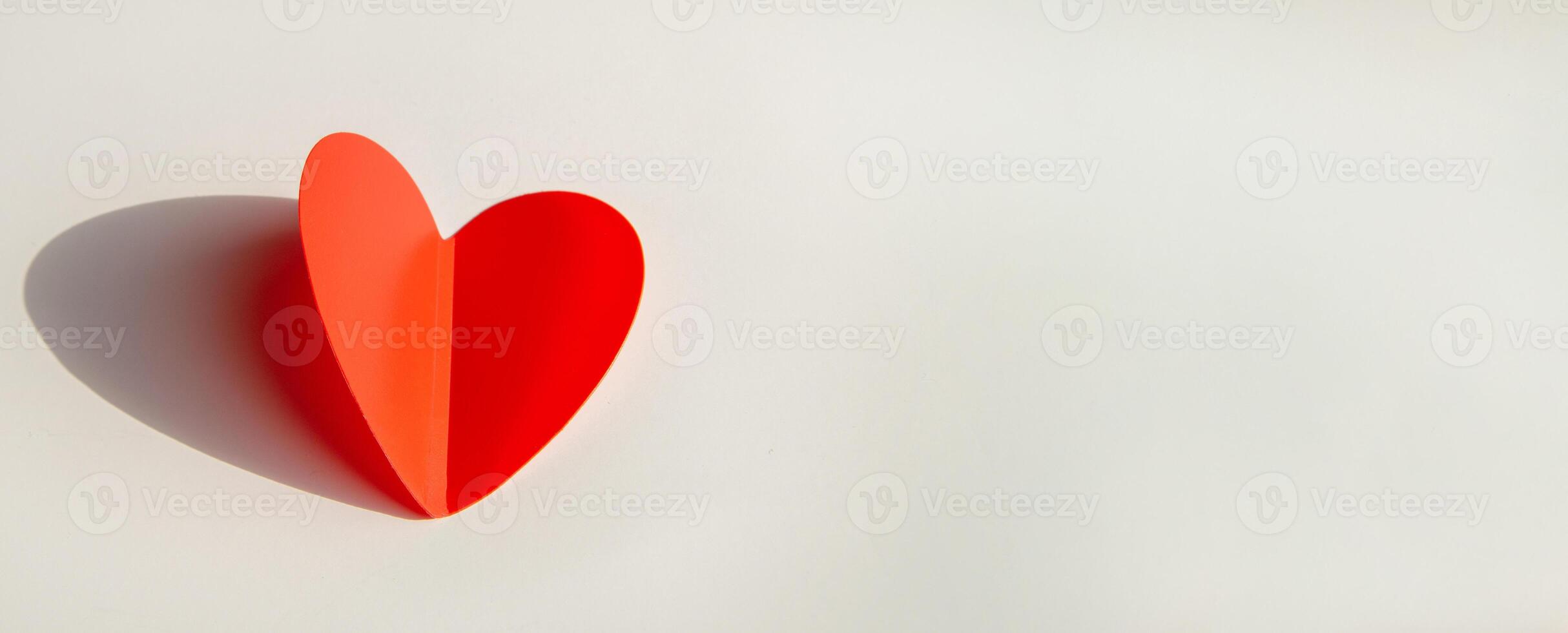 Banner with paper decoration in the shape of a red heart on a white background. Flat plan, top view, space for text on the right side. photo
