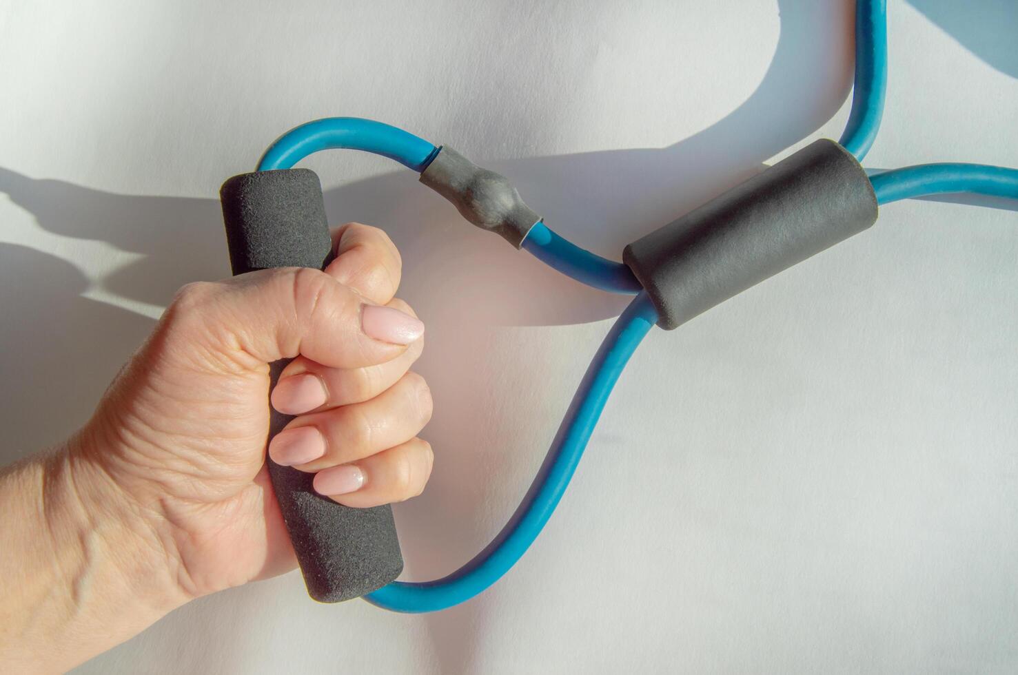 A woman's hand squeezes a rubber strength training espander, demonstrating arm exercises to improve fitness and rehabilitation photo