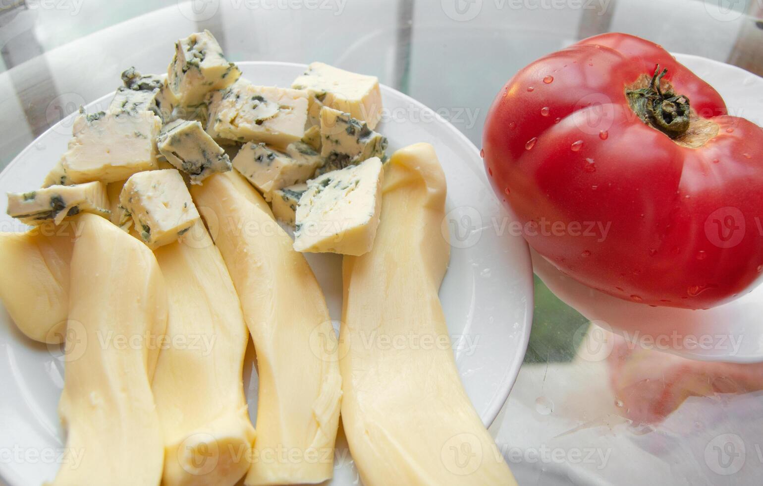 Different kinds of cheese on the plate and one red tomato, appetizers photo
