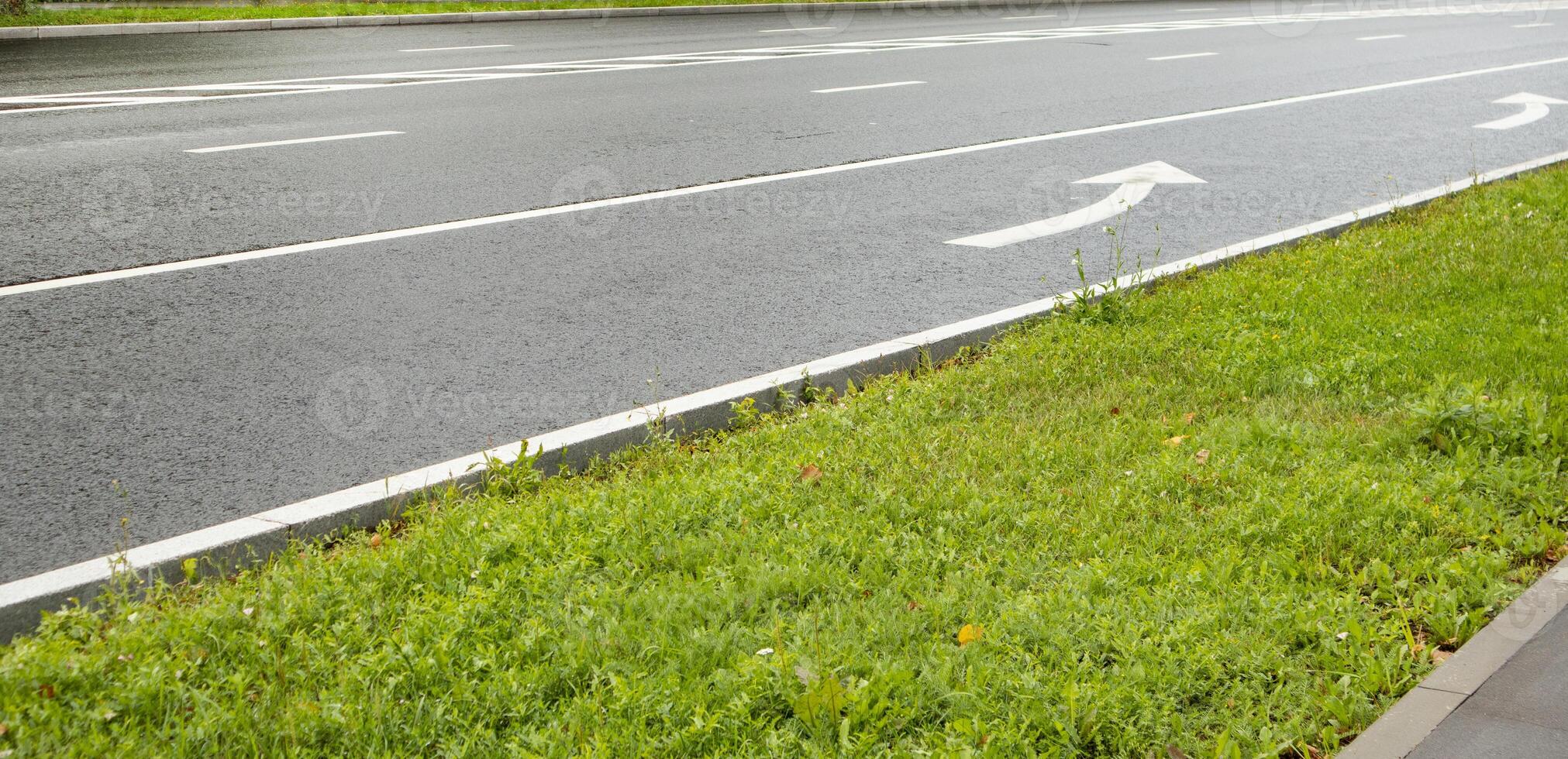 Asphalt roadway with an arrow pointing to the end of the lane pointing to the left. photo