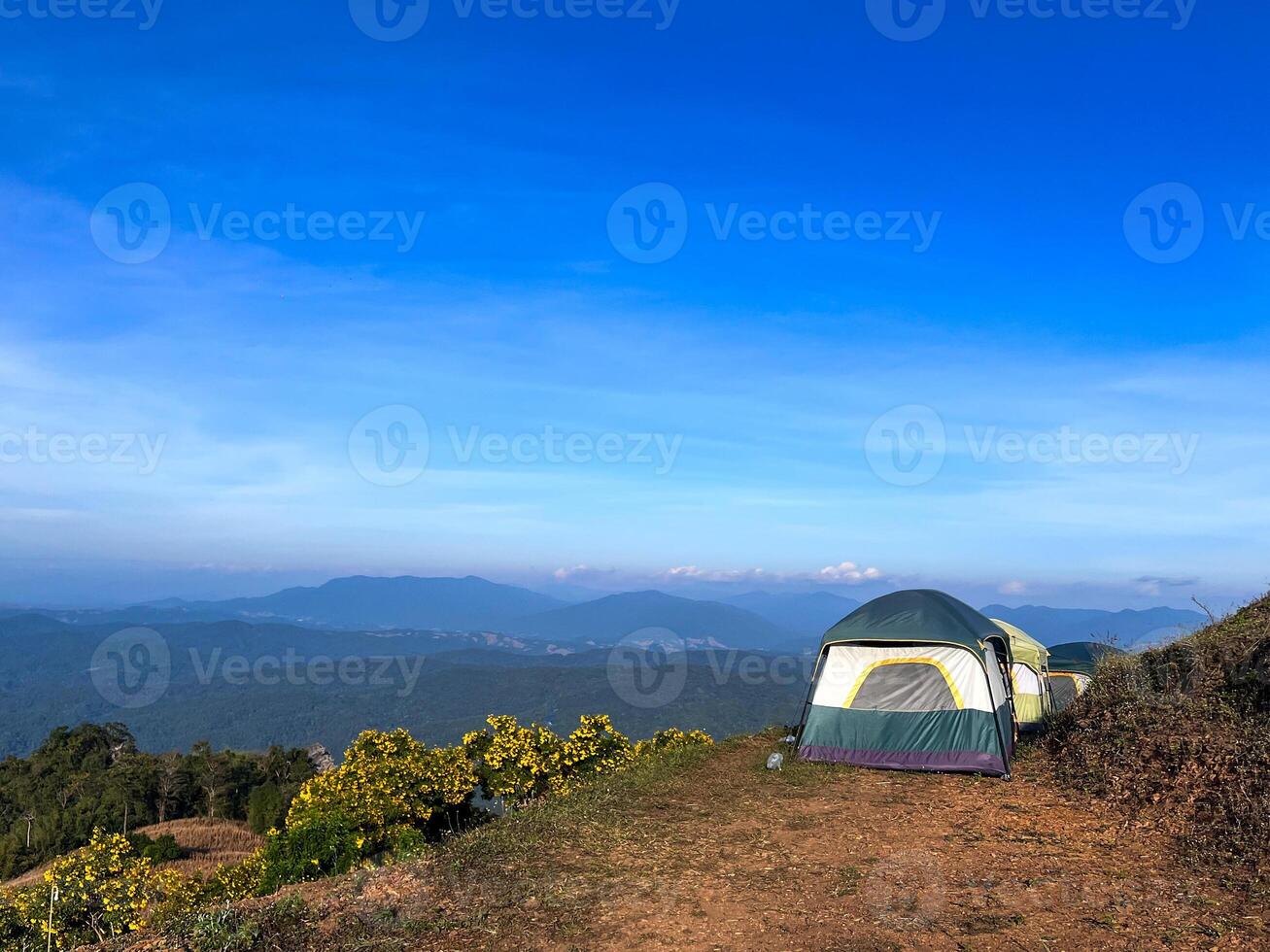 Row of tents located on the top of the hill with the panorama view of mountain and clear blue sky in background photo