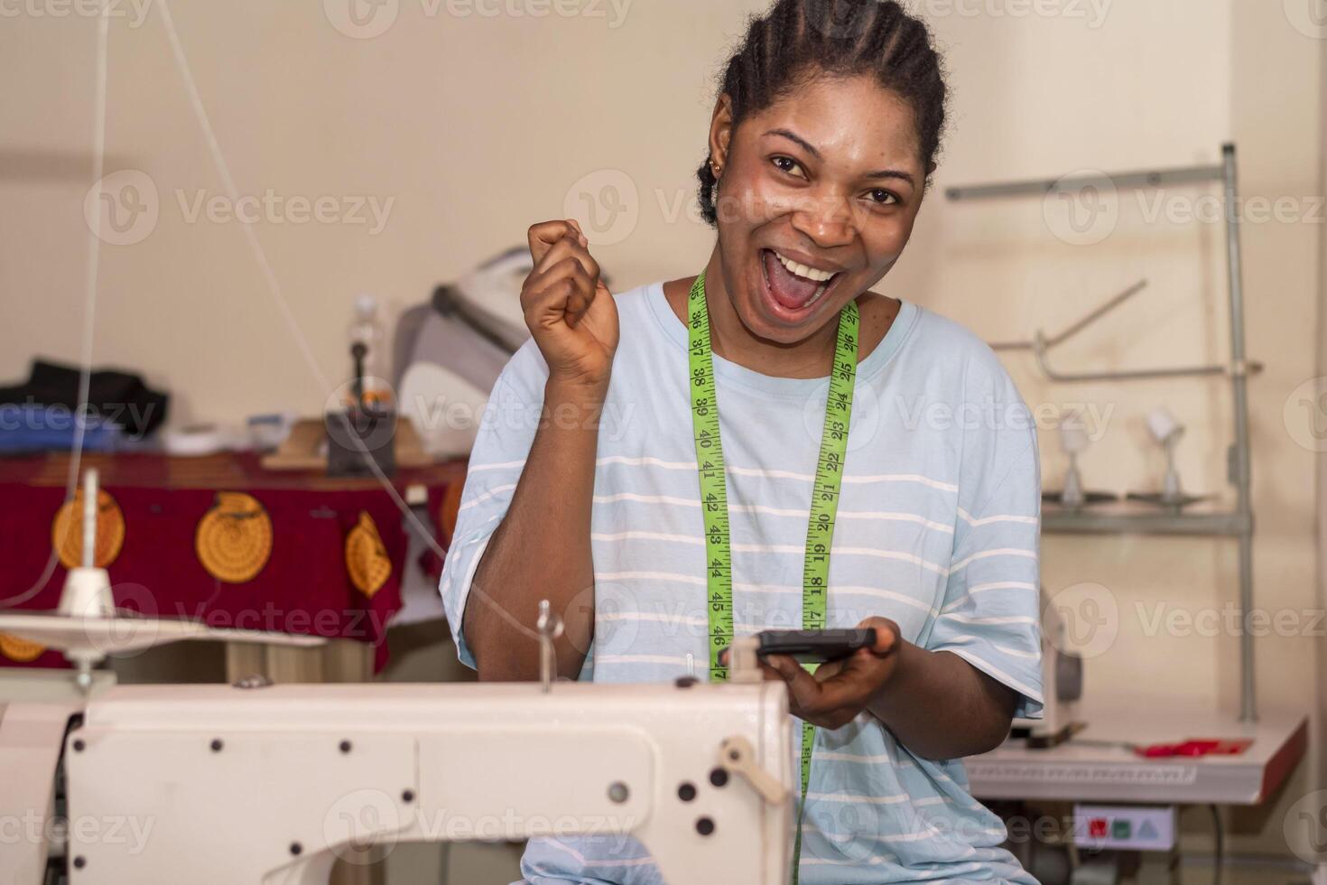 smart female dressmaker using her phone while working with sewing machine photo