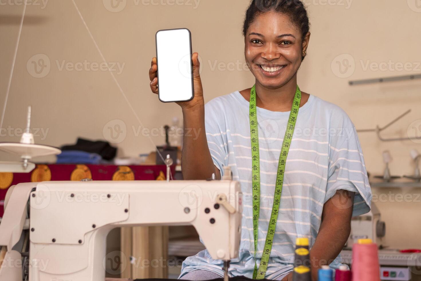 cute black tailor woman smiling while using his phone on machine photo