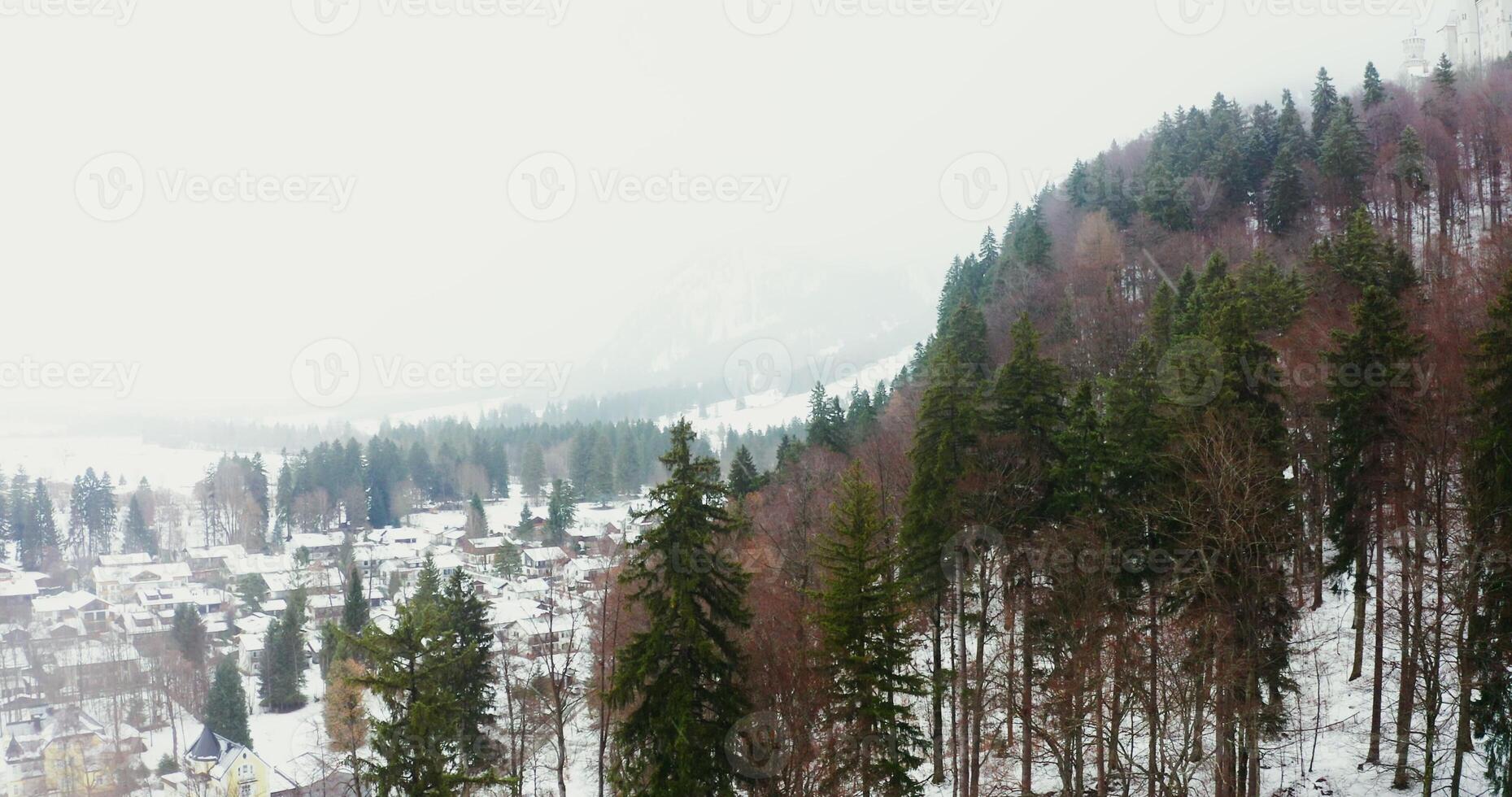 Small European town with cottage development at the foot of a hill with an old castle on top. filming from a quadcopter on a snowy winter day. photo