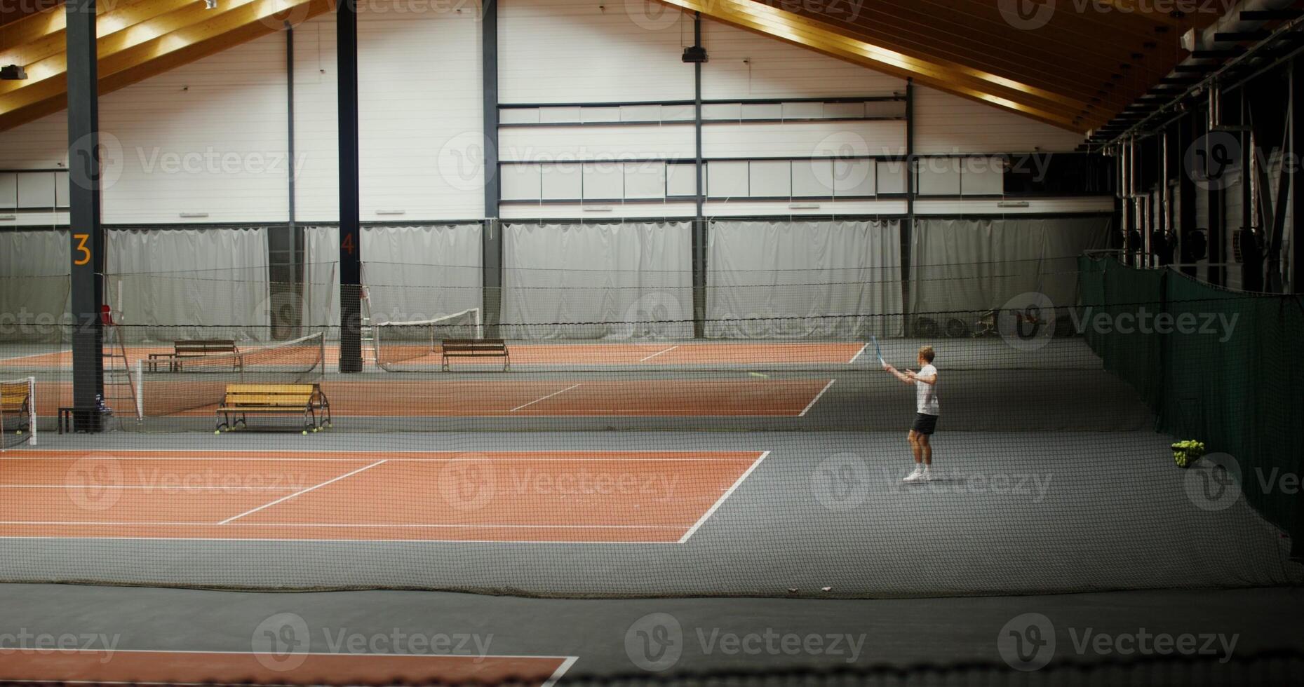 A young man of European appearance plays on one of the tennis courts in the indoor gym photo