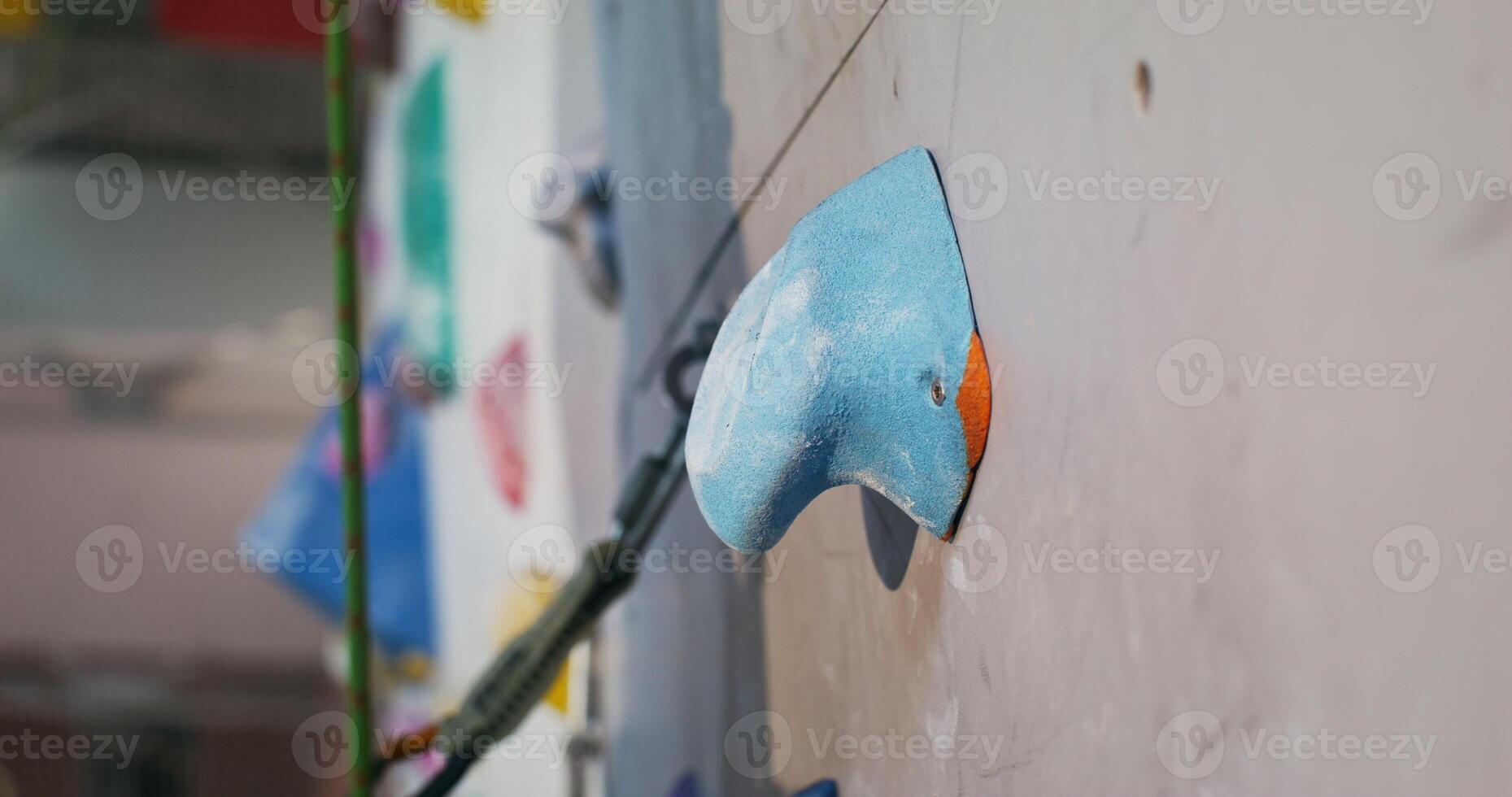 Man's foot in rubberized sports shoes steps on an artificial unevenness imitating a stone on a climbing wall, close up. Details of climbing the wall in the indoor climbing wall photo