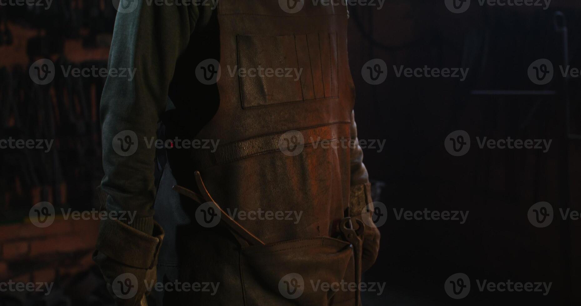 Blacksmith in protective gear and goggles is standing in the workshop photo