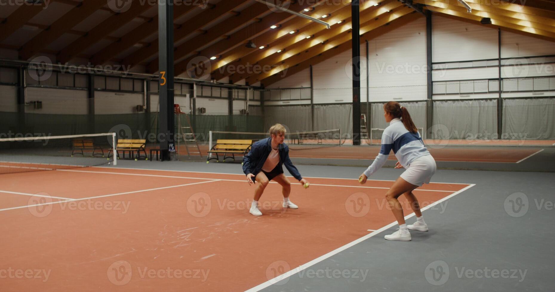 Young woman trainer throws tennis balls to young man in turn photo
