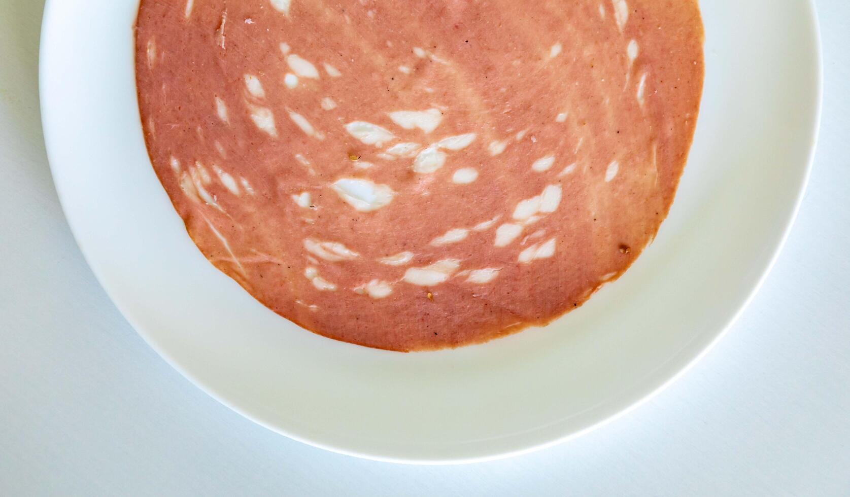 Close-up of a sliced bologna on a white plate top view photo
