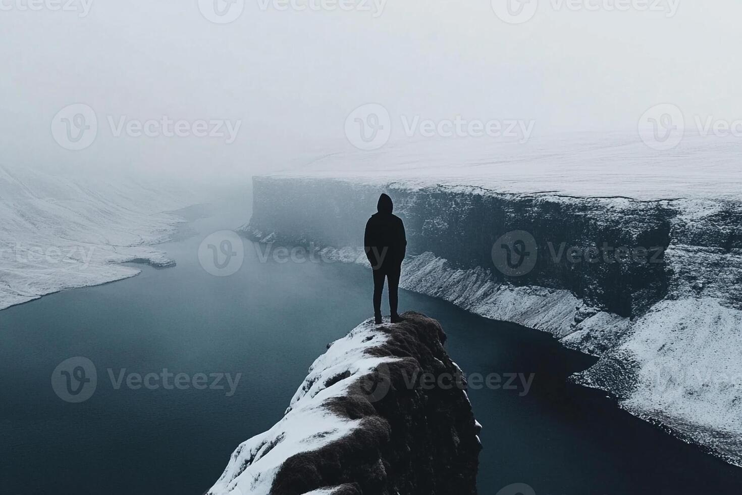 A person standing on top of a cliff overlooking a river photo
