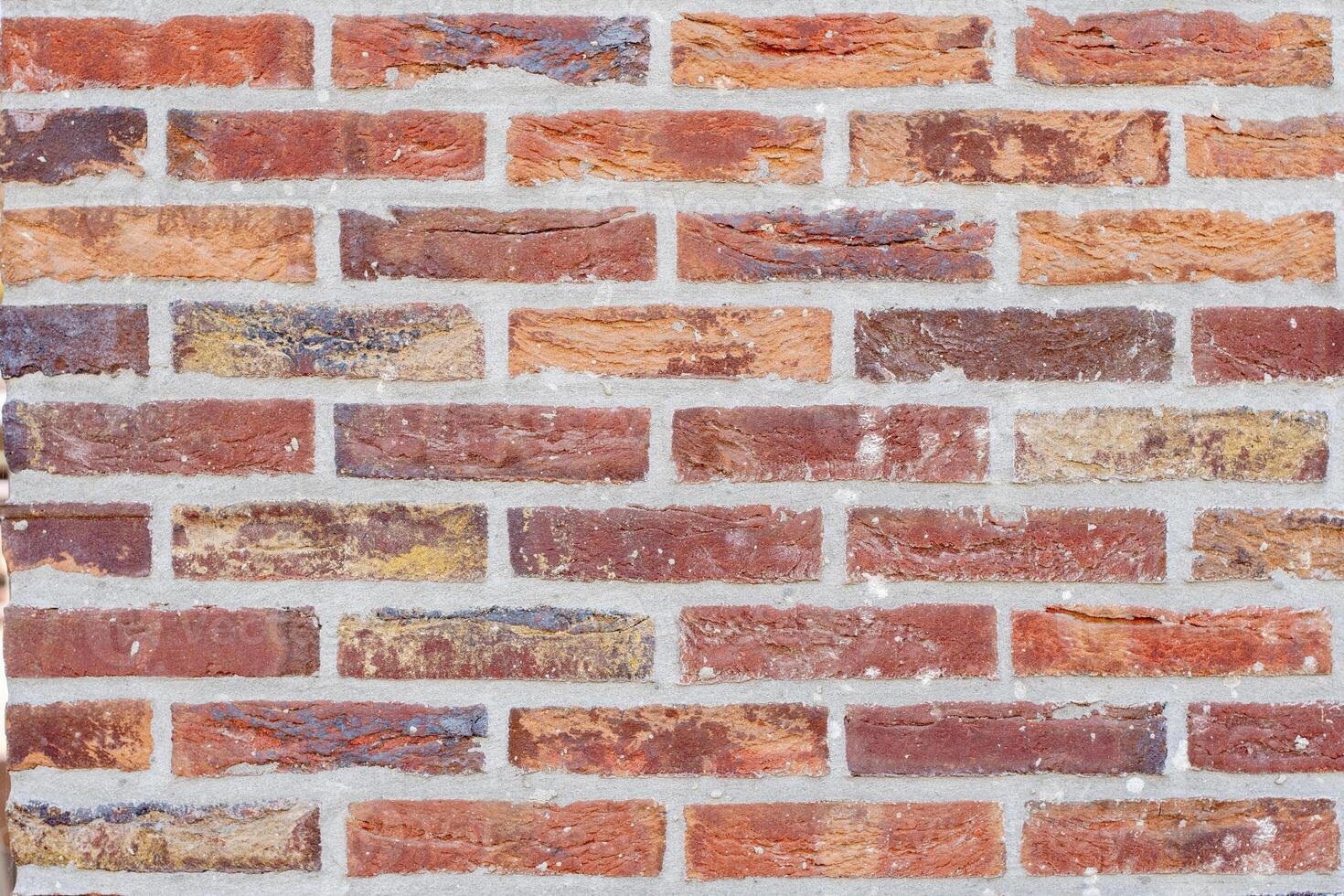 A wall of bricks in different shades of red and brown with repeating pattern of stretcher bricks, attractive textured background in rustic style photo