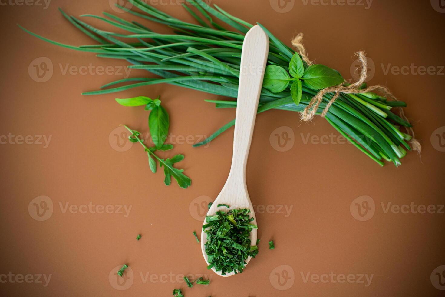 Top view of dried herbs and fresh green onions on brown background . photo